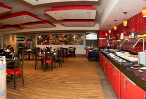 A restaurant with a buffet, wooden flooring, and red and beige decor. - Comfort Inn Puebla Centro Historico (Puebla)