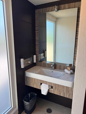 A modern bathroom with a large mirror, a sink, and a towel rack. - Comfort Inn Puebla Centro Historico (Puebla)