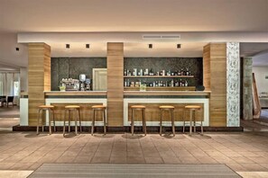 Eine Bar mit Hockern, einer Theke und einer Flaschenwand.