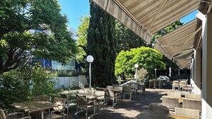 An outdoor patio with wicker furniture and a covered area. - Select Hotel Mainz (Mainz)