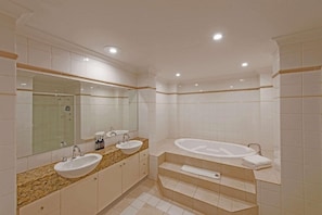Un baño moderno con dos lavamanos, un espejo grande y una bañera.