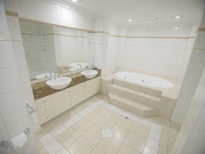 Un baño moderno con dos lavamanos, una bañera grande y un espejo sobre los lavamanos.