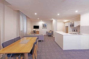 A modern hotel room with a dining area, a sofa, a TV, and a kitchenette. - Mantra Adelaide Central (Adelaide)