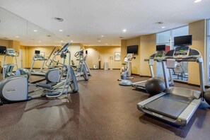 Uma academia com esteiras, elípticos e bolas de exercício.