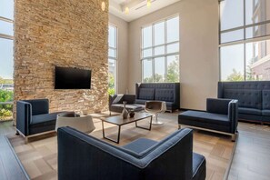 A modern lounge area with stone walls, large windows, and contemporary furniture. - Cambria Hotel Ft Collins (Fort Collins)