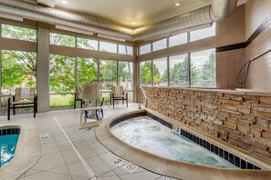 A spa area with a hot tub, seating, and a stone wall. - Cambria Hotel Ft Collins (Fort Collins)