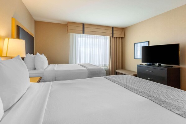 A hotel room with two beds, a TV, a desk, and a window with curtains. - Cambria Hotel Ft Collins (Fort Collins)