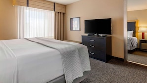 A hotel room with a bed, a flat-screen TV, a dresser, and a mirror. - Cambria Hotel Ft Collins (Fort Collins)