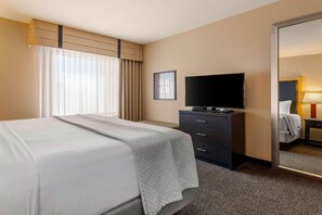 A hotel room with a bed, a flat-screen TV, a dresser, and a mirror. - Cambria Hotel Ft Collins (Fort Collins)