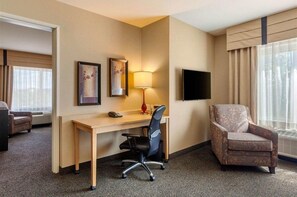 A hotel room with a desk, chair, TV, and large window. - Cambria Hotel Ft Collins (Fort Collins)