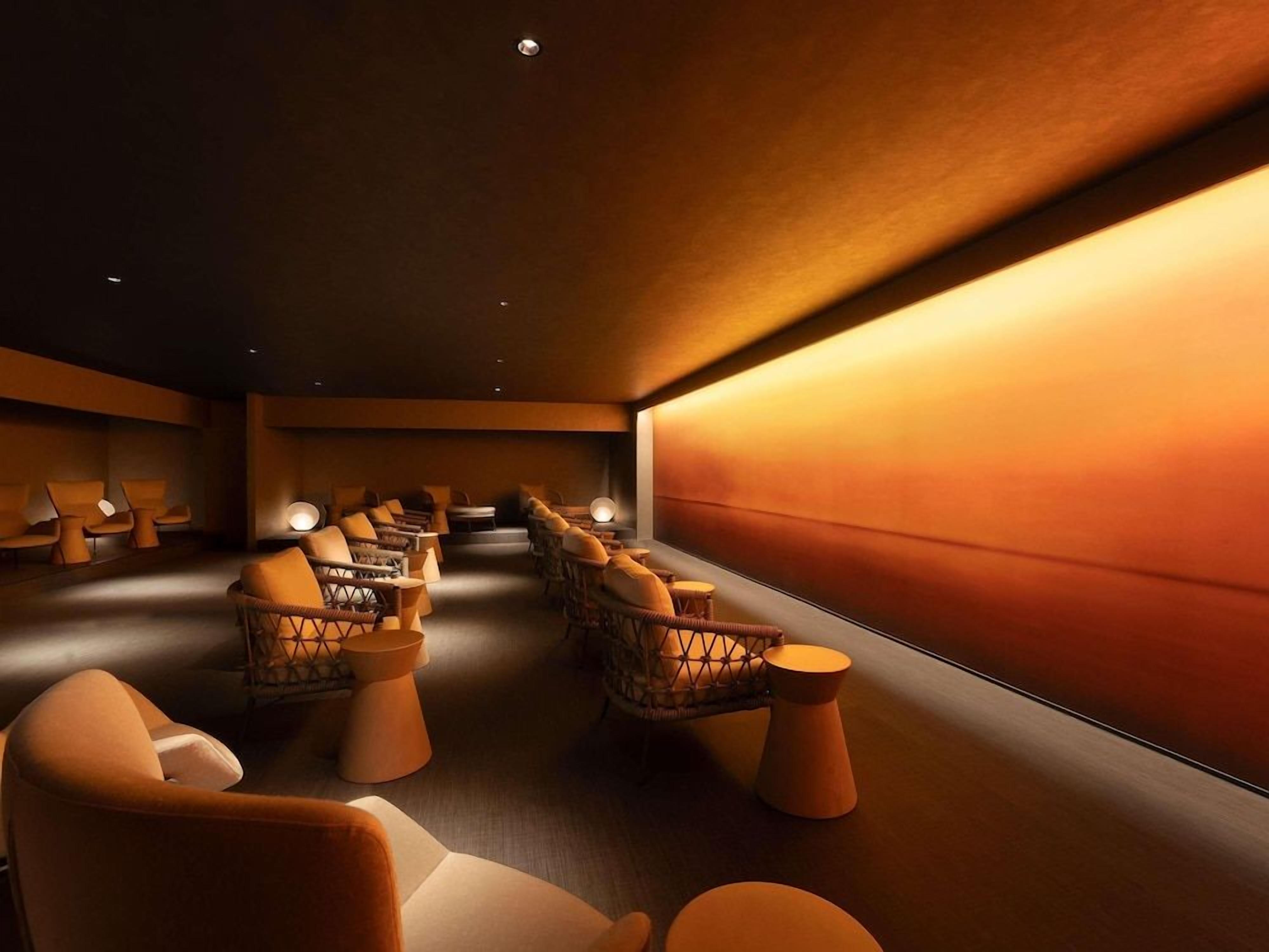A spa room with multiple seating areas, including cushioned chairs and a sofa, arranged in a row.