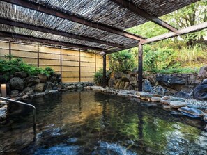 A traditional Japanese onsen with a wooden structure, a stone-lined pool, and a bamboo wall. - Grand Mercure Awaji Island Resort & Spa (Minamiawaji)
