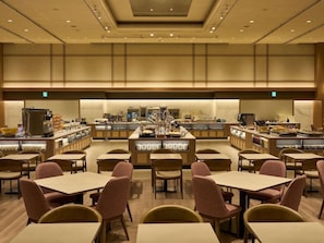 A hotel dining area with multiple tables and chairs, a central buffet station, and a ceiling with recessed lighting. - Grand Mercure Awaji Island Resort & Spa (Minamiawaji)