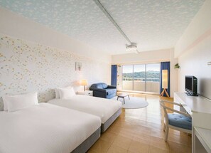 Habitación de hotel con dos camas, un escritorio, una silla, un televisor y un balcón con vistas.