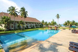 A resort with a swimming pool, palm trees, and a building with a tiled roof. - The Nouveau Chumphon Beach Resort and Golf (Chumphon)