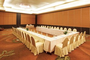 Uma sala de conferências com uma mesa comprida, cadeiras e piso coberto por carpete.