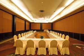 A conference room with a long table, chairs, and a carpeted floor.