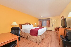 A hotel room with a bed, desk, chair, television, and a door. - Hotel Boerne (Boerne)