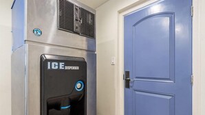 A water dispenser with a blue button and a logo on a wall.