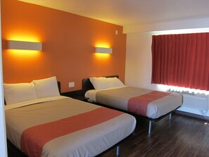 Une chambre d’hôtel avec deux lits, une fenêtre avec des rideaux rouges et des lampes fixées au mur.