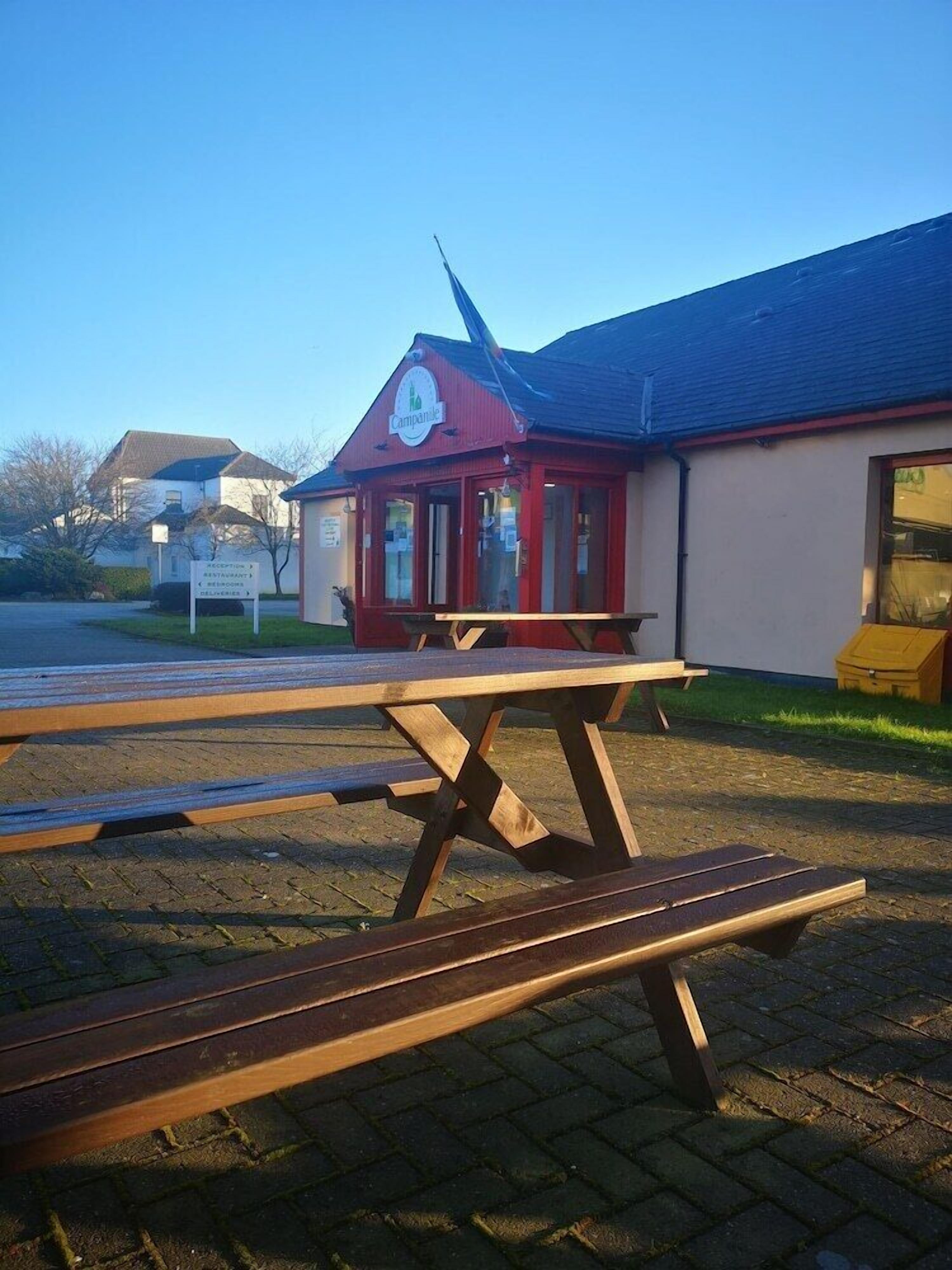 Un bâtiment rouge et blanc avec une enseigne indiquant « Campanile ». Devant, on trouve des tables de pique-nique.