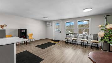 A modern kitchen with a dining area, a refrigerator, and a coffee machine.