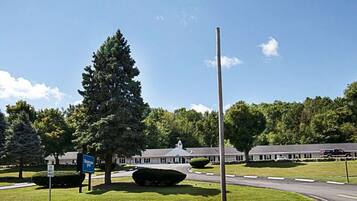 A road leading to a building with a sign for a motel. There are trees and a clear sky.