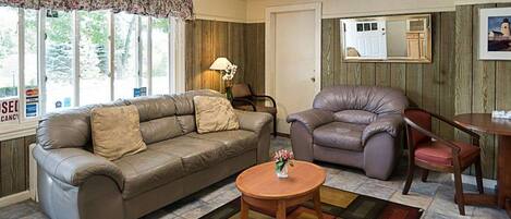 A living room with a sofa, armchair, and a small round table.