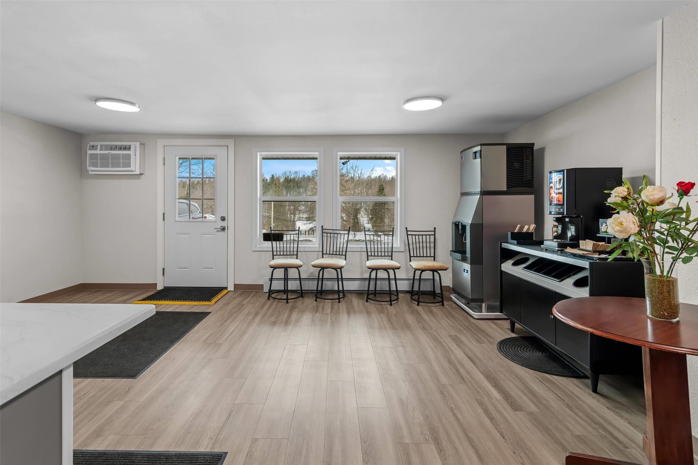 A compact kitchen with a dining area, a refrigerator, and a coffee machine.