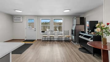 A compact kitchen with a dining area, a refrigerator, and a coffee machine.