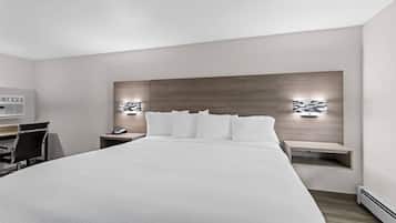 A modern hotel room with a large bed, a desk, and two bedside tables with lamps.