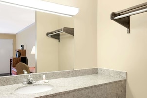Un baño con encimera de granito, un lavabo blanco, un espejo y un perchero para toallas.