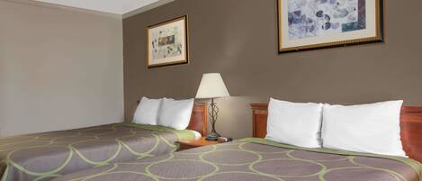 A hotel room with a bed, a nightstand, a lamp, and two framed pictures on the wall.