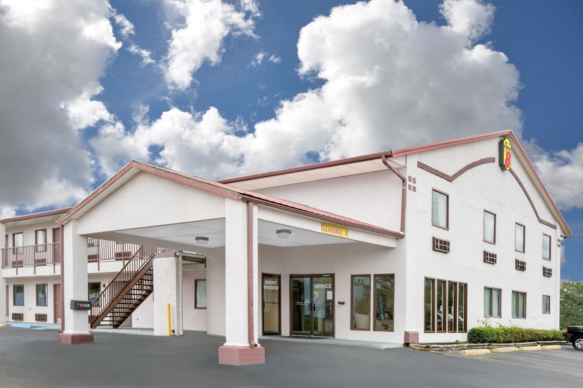 A hotel with a covered parking area, a staircase, and a sign indicating 'Clearance 9'.