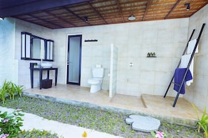 A bathroom with a sink, mirror, toilet, and shower area.