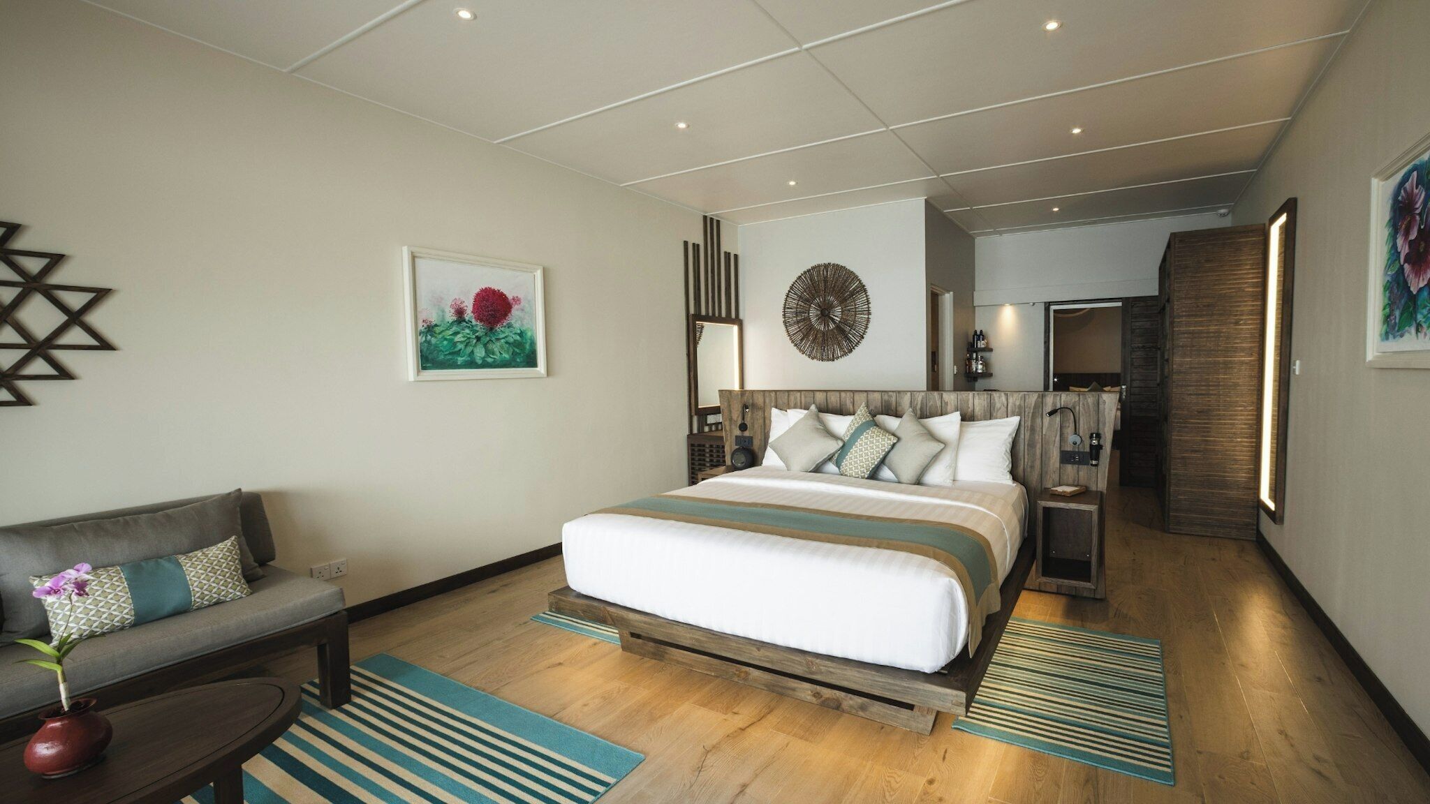Une chambre d’hôtel moderne avec un grand lit, un canapé, une table basse et une petite table d’appoint.
