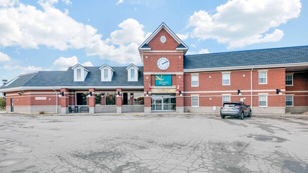 A hotel with a clock tower, a restaurant, and a parking lot.