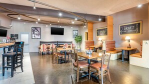 A modern restaurant interior with booths, tables, and a bar area.