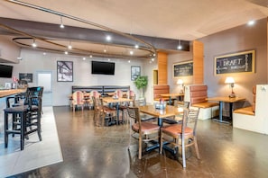 A modern restaurant interior with booths, tables, and a bar area.