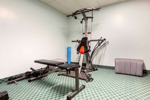 Un gimnasio con equipo de ejercicio, una banca y una banca acolchada.