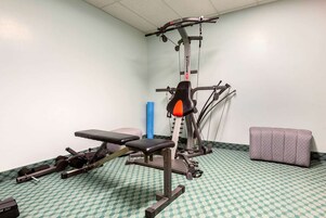A gym with exercise equipment, a bench, and a padded bench.