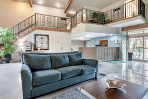 A spacious living area with a large sofa, a coffee table, and a staircase leading to an upper level.