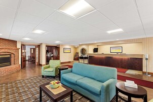 Un vestíbulo de hotel con mostrador de recepción, chimenea, sofá y zona de comedor.