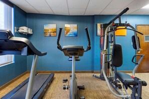 Un gimnasio con cinta de correr, elíptica y máquina de pesas.