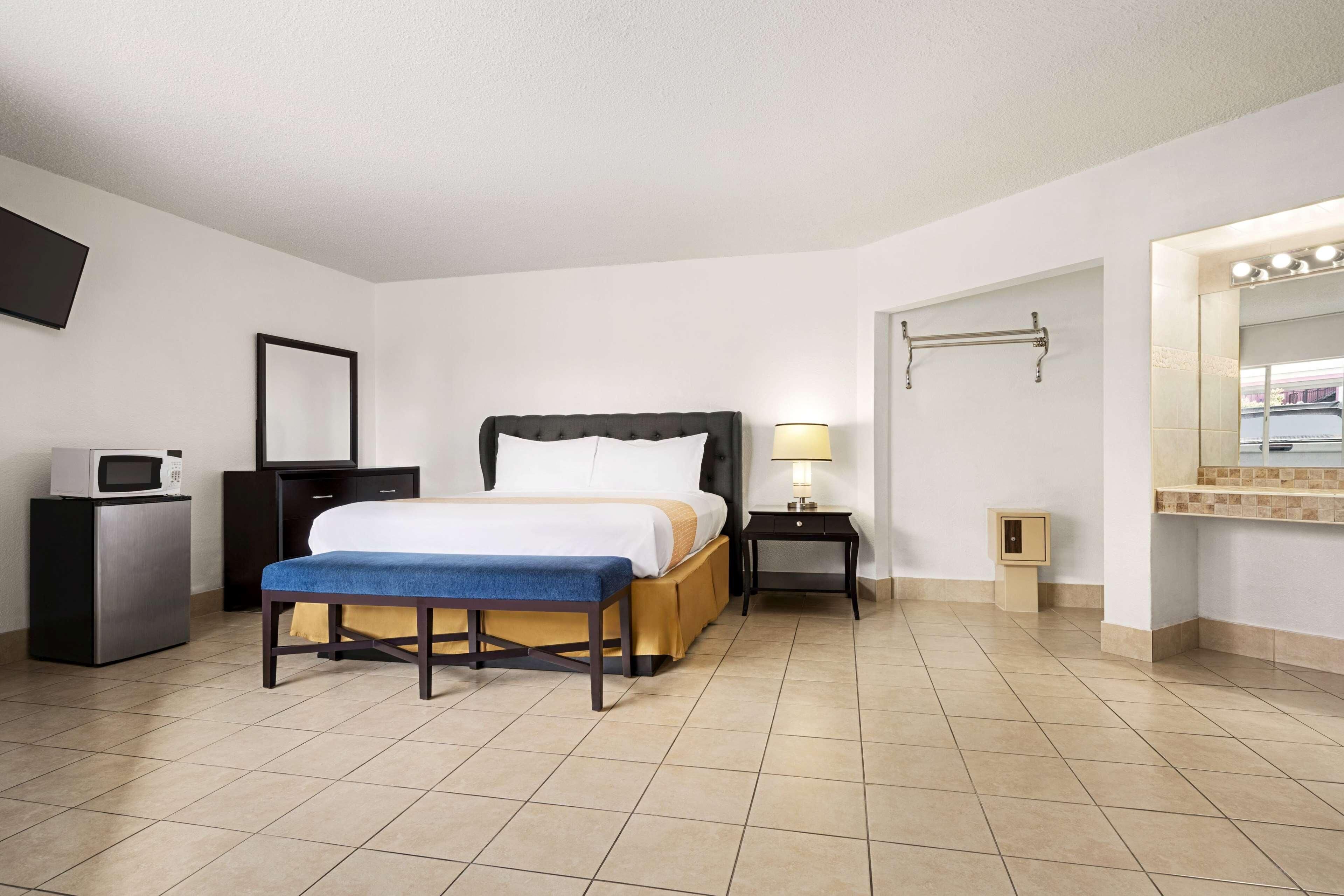 A hotel room with a bed, bedside table, lamp, and a small cabinet.