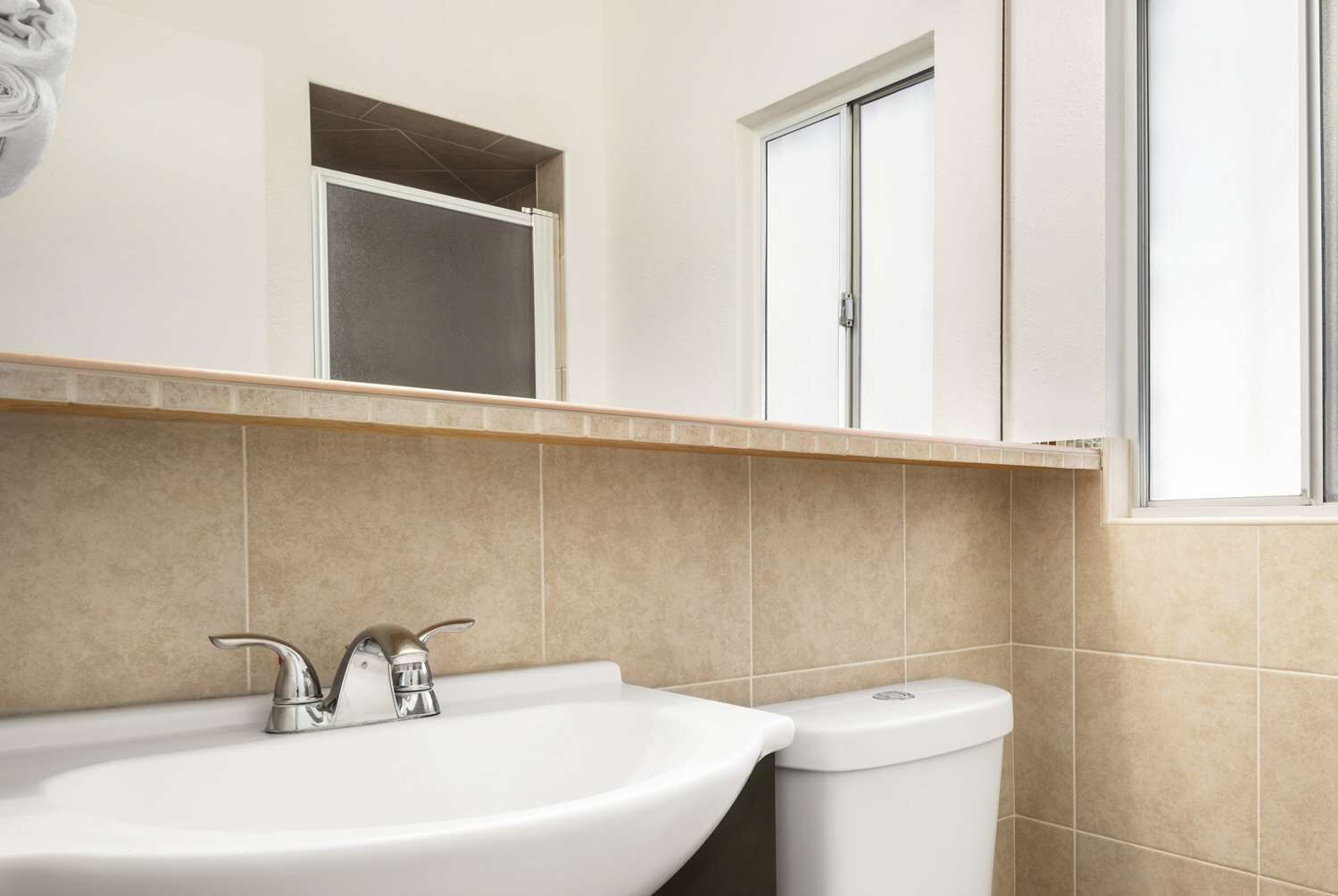 A bathroom with a sink, toilet, and a window.