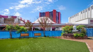 A well-maintained lawn with a bench, a fenced area, and a building with a red and white facade.