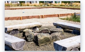 A sandy beach area with wooden benches and large rocks.