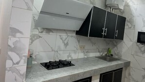 A kitchen with a gas stove, black cabinets, and a white range hood.