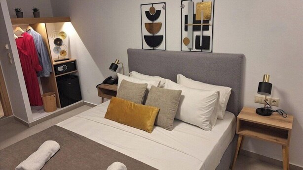 Una habitación de hotel con cama, mesitas de noche, armario y obras de arte en las paredes.